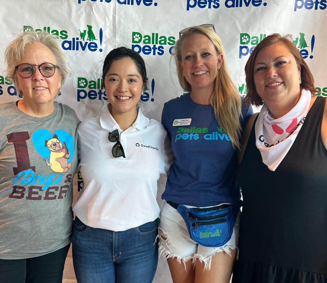 Viridiana Duran, marketing director of GoodCharlie, poses for a photo with Dallas Pets Alive (DPA) representatives. There is a DPA backdrop behind them.