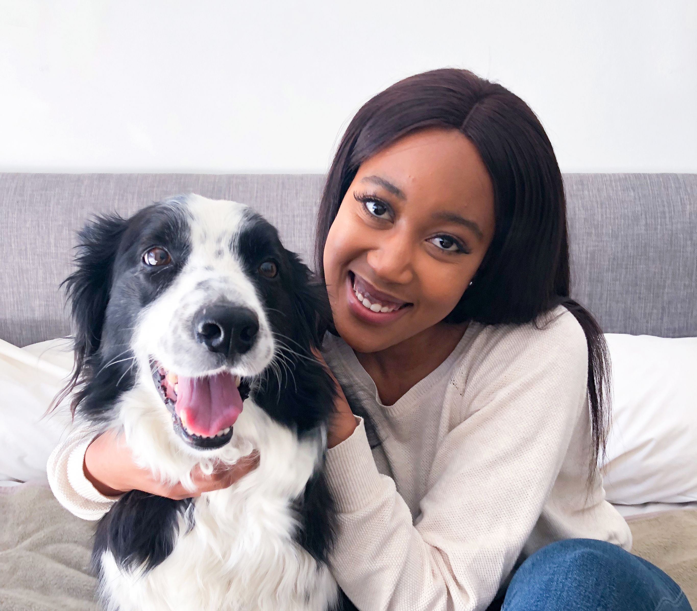 A woman smiling with a dog that has black and white fur.